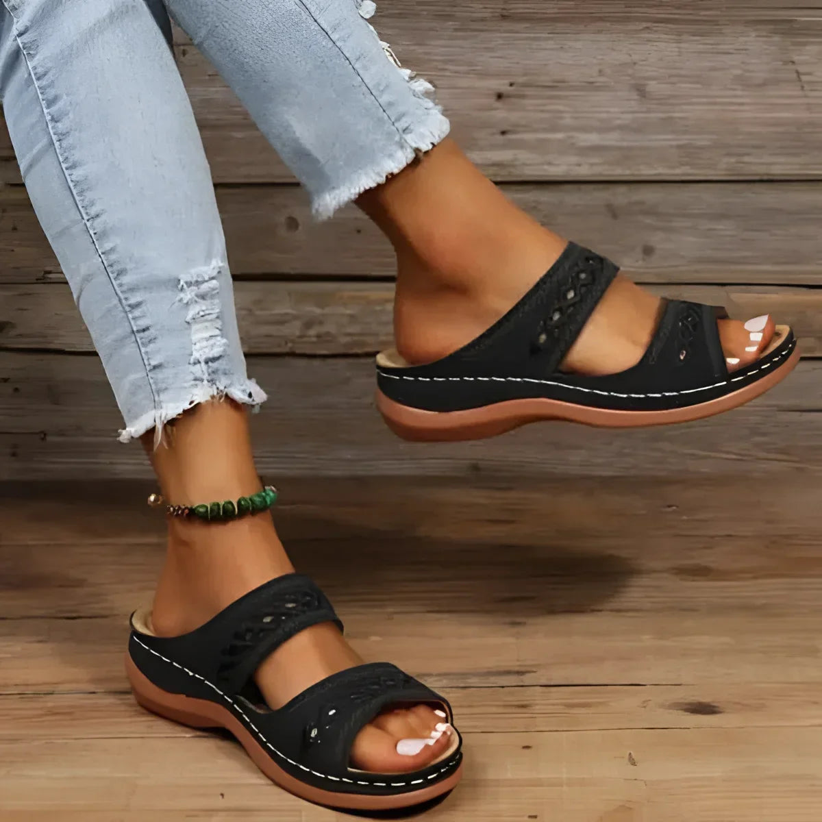 Sandales à enfiler en cuir noir avec deux brides et des perforations décoratives.