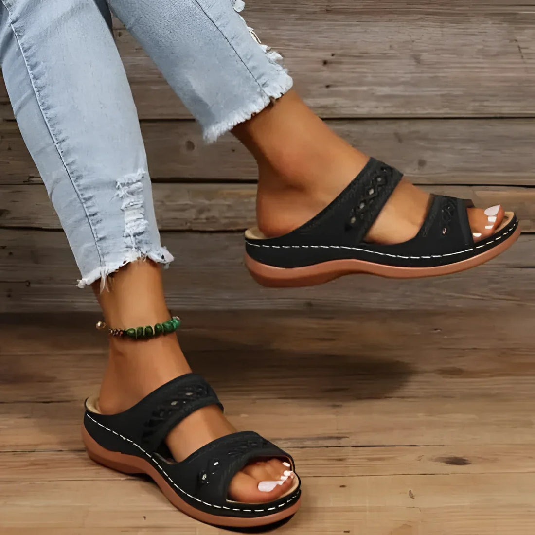 Sandales à enfiler en cuir noir avec deux brides et des perforations décoratives.
