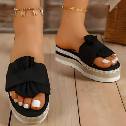 Sandales à plateforme noires avec semelles blanches et bracelet de cheville doré visible.
